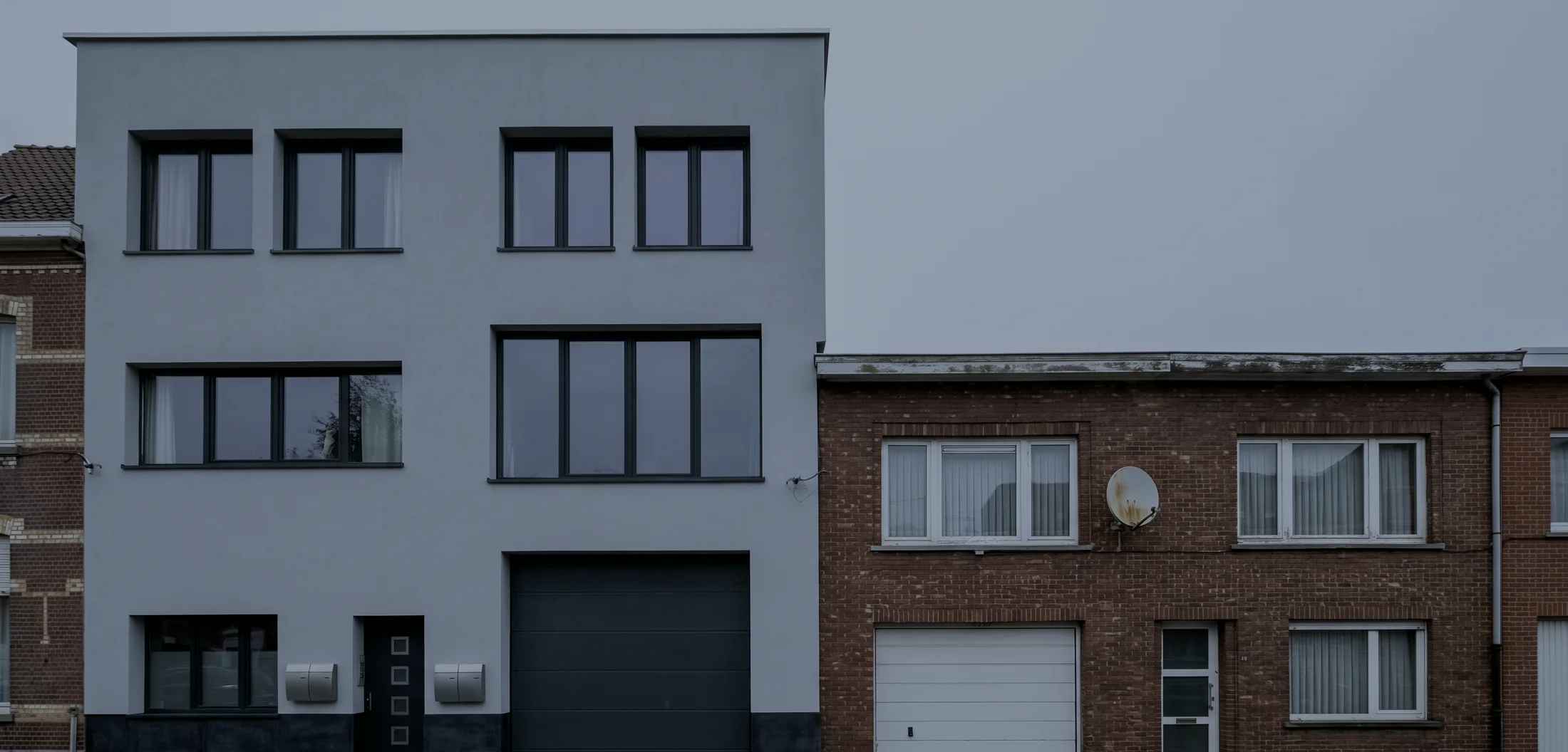Een gerenoveerde rijwoning in Antwerpen, afgewerkt met crepi over gevelisolatie, naast een woning in oude rode baksteen.