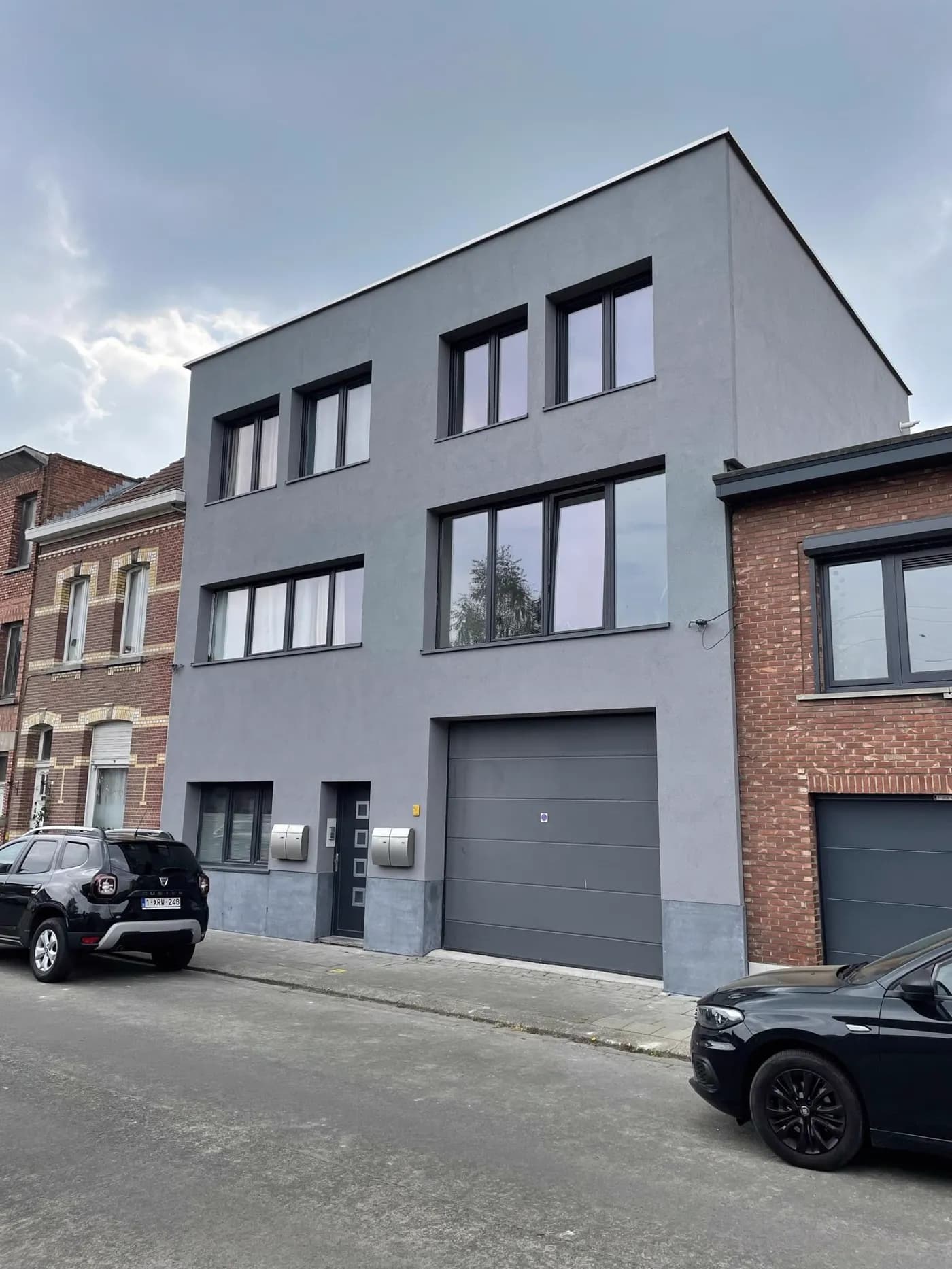 Een woning in Antwerpen na gevelisolatie met crepi, naast een onbehandelde bakstenen buur.