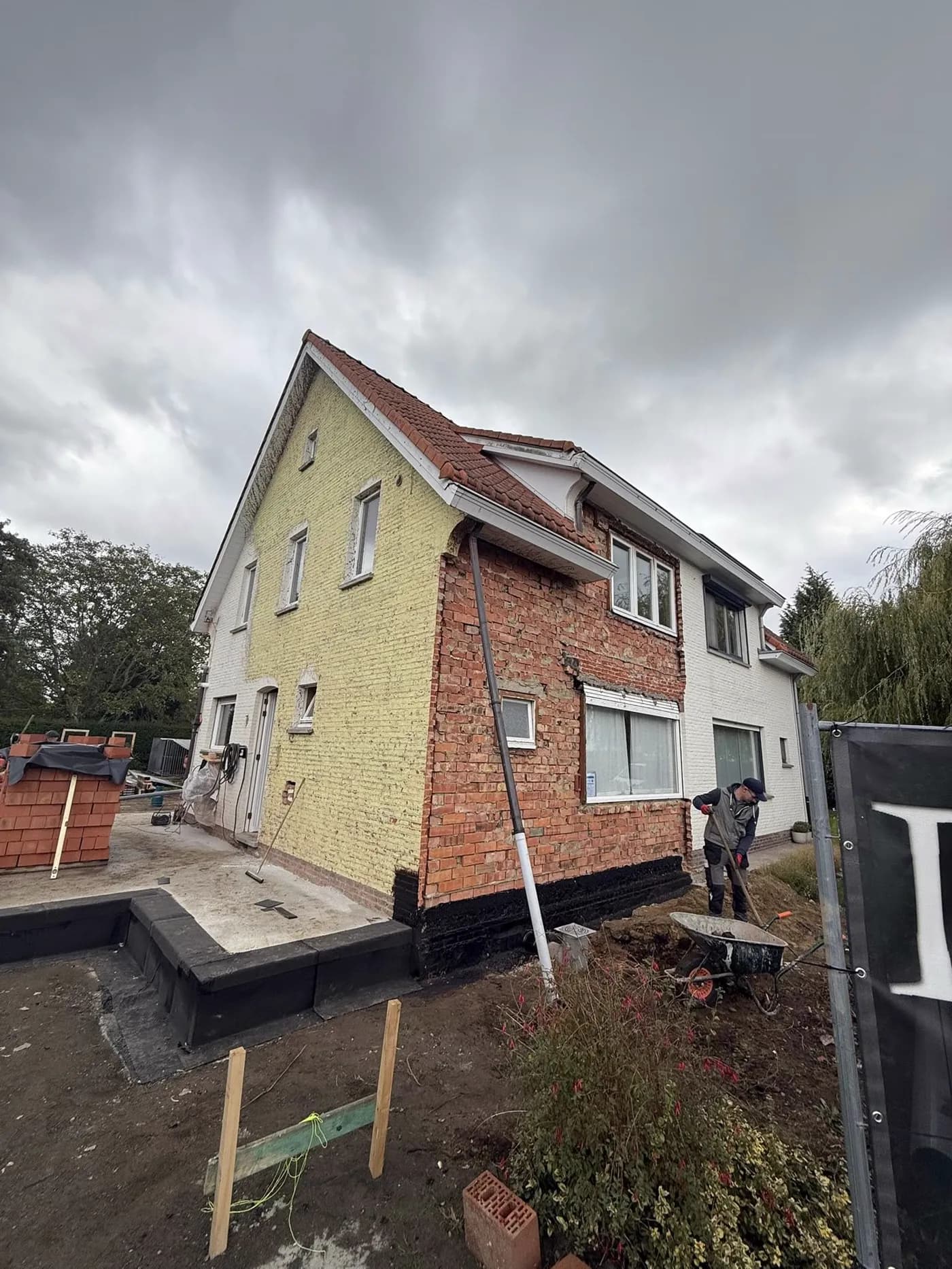 Een woning in werken, met een nieuwe uitbouwvloer en pallets gevelsteen op het terrein.